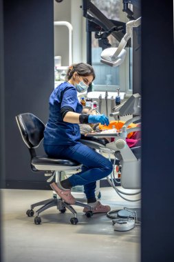 Diş muayenehanesinde genç bir dişçi. İşte bir dişçi. Diş tedavisi konsepti. Yüksek kalite fotoğraf. Çocuk dişini tedavi eden genç bir dişçi, dişçi ofisinde oturan küçük bir kız..