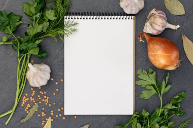 Boş defterle malzemeler pişiriyorum. Şifalı bitkiler ve baharatlarla dolu bir yemek tarifi kitabı. Yüksek kalite fotoğraf. Uzayı kopyala Üst manzara, düz yatış. Yemek pişirme hazırlığı.