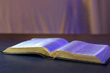 Masanın üzerinde İncil 'i aç. Din kavramı. Siyah arka planda İncil. Yüksek kalite fotoğraf. Tanrıya ibadet etmek, dua etmek ve evde İncil okumak..