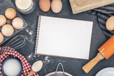 Pişirme malzemeleri ve boş kitaplarla dolu bir arka plan. Pişirme malzemeleri. Yüksek kalite fotoğraf. Uzayı kopyala Karanlık bir arka planda yemek malzemeleri. Üst manzara, düz uzanma.