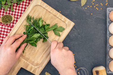 Ahşap kesme tahtasıyla maydanoz kesen kadın eller. Yemek malzemeleriyle donatılmış bir geçmiş. Yüksek kalite fotoğraf. Uzayı kopyala Üst manzara, düz uzanma.