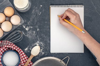 Pişirme malzemeleri ve boş kitaplarla dolu bir arka plan. Pişirme malzemeleri. Yüksek kalite fotoğraf. Uzayı kopyala Karanlık bir arka planda yemek malzemeleri. Üst manzara, düz uzanma.