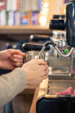 Kahve makinesiyle süt buharı yapan barista. Kafede kahve yapan bayan barista. Yüksek kalite fotoğraf. Kahve makinesinde süt içen kadın kahveci elleri. Kahve hazırlıyorum..