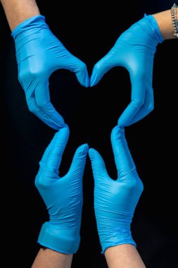 Diş hekimliği. Diş tedavisi. Ellerin dişin şeklini gösteriyor. Yüksek kalite fotoğraf. Mavi eldivenli eller diş şeklini, dişçilik konseptini gösteriyor. Siyah arka plan. Boşluğu kopyala.