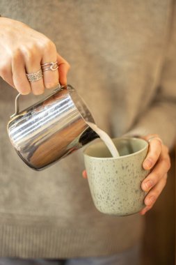 Kahveci Latte sanatı için süt dolduruyor. Baristalar kahveyi yakından hazırlar. Yüksek kalite fotoğraf. Bir kafede profesyonel kahve hazırlığı. Kahveli sütlü kahve yapan kadın..