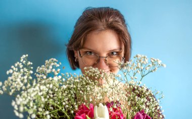 Elinde buket olan genç bir kadın. Kadınlar Günü 'nde. Sevgililer Günü. Yüksek kalite fotoğraf. Sade arka planda çiçekleri olan çekici bir kadın. 8 Mart Kutlaması.