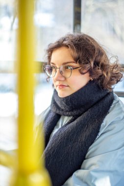 Bir kız öğrenci toplu taşımaya biniyor. Toplu taşıma ve insan konsepti. Yüksek kalite fotoğraf. Gözlüklü bir kız toplu taşımaya biniyor..