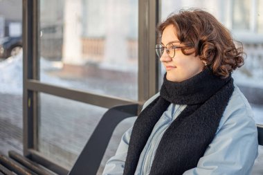 Genç kız toplu taşıma için bekliyor. Otobüs durağındaki kız. Yüksek kalite fotoğraf. Soğuk hava. Öğrenci bir kız otobüs bekliyor. Boşluğu kopyala.