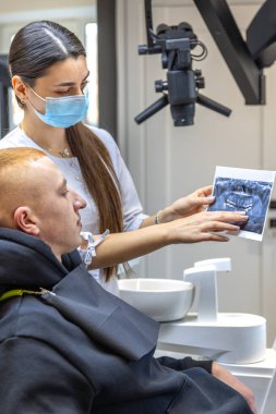 Genç bir dişçi hastaya diş röntgenini gösteriyor. Dişçi konsepti. Yüksek kalite fotoğraf. İşte bir dişçi. Dişçi ve hasta.