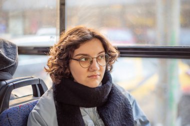 Bir kız öğrenci toplu taşımaya biniyor. Toplu taşıma ve insan konsepti. Yüksek kalite fotoğraf. Gözlüklü bir kız toplu taşımaya biniyor..