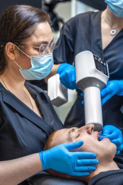 Bir diş hekimi takımı modern ekipmanları kullanarak hastaların dişlerini tedavi eder. Dişçi konsepti. Yüksek kalite fotoğraf. Diş hekimliği ofisinde profesyonel diş tedavisi.