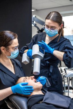 Bir diş hekimi takımı modern ekipmanları kullanarak hastaların dişlerini tedavi eder. Dişçi konsepti. Yüksek kalite fotoğraf. Diş hekimliği ofisinde profesyonel diş tedavisi.
