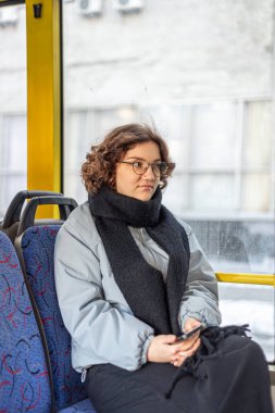 Bir kız öğrenci toplu taşımaya biniyor. Toplu taşıma ve insan konsepti. Yüksek kalite fotoğraf. Gözlüklü bir kız toplu taşımaya biniyor..