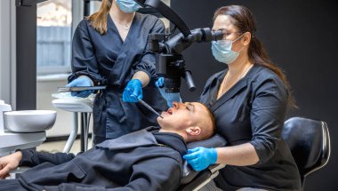 Bir diş hekimi takımı modern ekipmanları kullanarak hastaların dişlerini tedavi eder. Dişçi konsepti. Yüksek kalite fotoğraf. Diş hekimliği ofisinde profesyonel diş tedavisi.