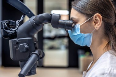 Genç bayan dişçi hastaların dişlerini diş mikroskobuyla tedavi ediyor. Dişçi konsepti. Yüksek kalite fotoğraf. Profesyonel diş tedavisi. Diş ekipmanları.