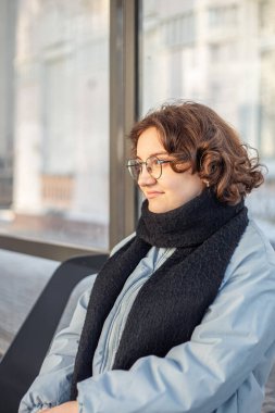 Genç kız toplu taşıma için bekliyor. Otobüs durağındaki kız. Yüksek kalite fotoğraf. Soğuk hava. Öğrenci bir kız otobüs bekliyor..