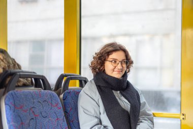 Bir kız öğrenci toplu taşımaya biniyor. Toplu taşıma ve insan konsepti. Yüksek kalite fotoğraf. Gözlüklü bir kız toplu taşımaya biniyor..