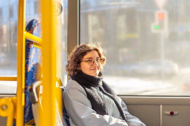 Bir kız öğrenci toplu taşımaya biniyor. Toplu taşıma ve insan konsepti. Yüksek kalite fotoğraf. Gözlüklü bir kız toplu taşıma aracına biniyor. Boşluğu kopyala.