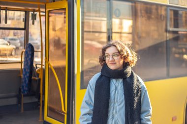 Toplu taşıma. Otobüsü bekliyorum. Öğrenci kız nakil için bekliyor. Yüksek kalite fotoğraf. Gözlüklü ve ceketli kız..