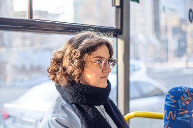 Bir kız öğrenci toplu taşımaya biniyor. Toplu taşıma ve insan konsepti. Yüksek kalite fotoğraf. Gözlüklü bir kız toplu taşımaya biniyor..