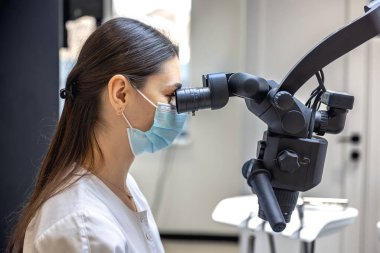 Genç bayan dişçi hastaların dişlerini diş mikroskobuyla tedavi ediyor. Dişçi konsepti. Yüksek kalite fotoğraf. Profesyonel diş tedavisi. Diş ekipmanları.