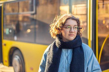 Toplu taşıma. Otobüsü bekliyorum. Öğrenci kız nakil için bekliyor. Yüksek kalite fotoğraf. Gözlüklü ve ceketli kız..