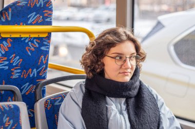 Bir kız öğrenci toplu taşımaya biniyor. Toplu taşıma ve insan konsepti. Yüksek kalite fotoğraf. Gözlüklü bir kız toplu taşımaya biniyor..