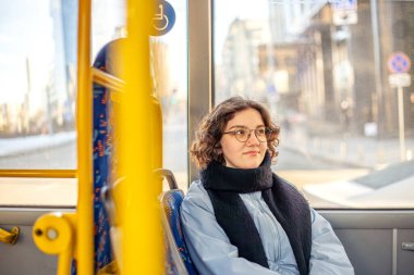 Bir kız öğrenci toplu taşımaya biniyor. Toplu taşıma ve insan konsepti. Yüksek kalite fotoğraf. Gözlüklü bir kız toplu taşımaya biniyor..