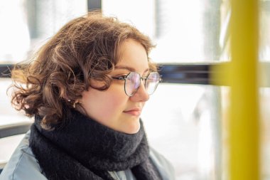 Bir kız öğrenci toplu taşımaya biniyor. Toplu taşıma ve insan konsepti. Yüksek kalite fotoğraf. Gözlüklü bir kız toplu taşımaya biniyor..