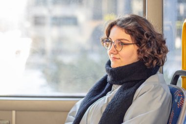 Bir kız öğrenci toplu taşımaya biniyor. Toplu taşıma ve insan konsepti. Yüksek kalite fotoğraf. Gözlüklü bir kız toplu taşıma aracına biniyor. Boşluğu kopyala.