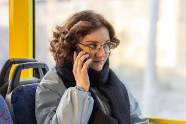Bir kız öğrenci toplu taşımaya biniyor. Toplu taşıma ve insan konsepti. Yüksek kalite fotoğraf. Bir kız elinde telefonla toplu taşıma aracına biniyor..