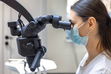 Genç bayan dişçi hastaların dişlerini diş mikroskobuyla tedavi ediyor. Dişçi konsepti. Yüksek kalite fotoğraf. Profesyonel diş tedavisi. Diş ekipmanları.