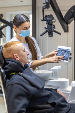 Genç bir dişçi hastaya diş röntgenini gösteriyor. Dişçi konsepti. Yüksek kalite fotoğraf. İşte bir dişçi. Dişçi ve hasta.