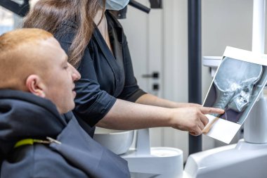 Genç bir dişçi hastaya diş röntgenini gösteriyor. Dişçi konsepti. Yüksek kalite fotoğraf. İşte bir dişçi. Dişçi ve hasta.