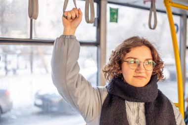 Toplu taşımacılıkta tırabzana tutunan genç bir kadın. Toplu taşıma. Yüksek kalite fotoğraf. Toplu taşıma ve insan kavramı.