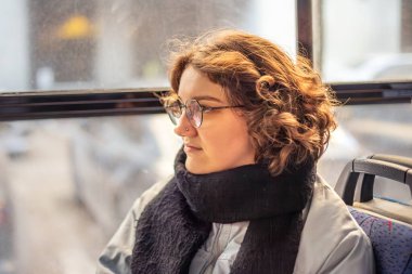 Bir kız öğrenci toplu taşımaya biniyor. Toplu taşıma ve insan konsepti. Yüksek kalite fotoğraf. Gözlüklü bir kız toplu taşımaya biniyor..