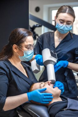 Bir diş hekimi takımı modern ekipmanları kullanarak hastaların dişlerini tedavi eder. Dişçi konsepti. Yüksek kalite fotoğraf. Diş hekimliği ofisinde profesyonel diş tedavisi.
