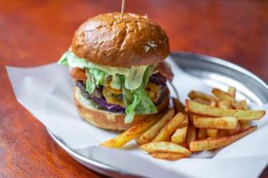 Hamburger yakın plan. Fast food ve hile yemek konsepti. Abur cubur. Yüksek kalite fotoğraf. Restoranda yapılmış bir hamburger. Sulu pirzola ve meyveli çörek..
