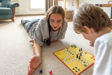 Küçük kardeşle masa oyunu oynayan bir kız. Masa oyunu. Yüksek kalite fotoğraf. Genç kız kardeşiyle masa oyunu oynuyor. Eğitim tahtası oyunu.