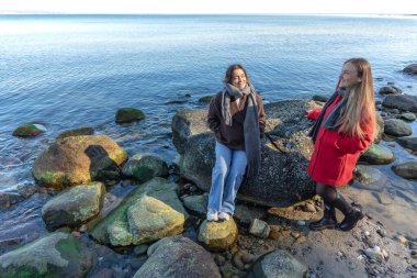 Deniz kıyısında yürüyen iki kadın. İki arkadaş eğleniyor ve birlikte vakit geçiriyorlar. Yüksek kalite fotoğraf. Doğada bir yürüyüş. Boşluğu kopyala.