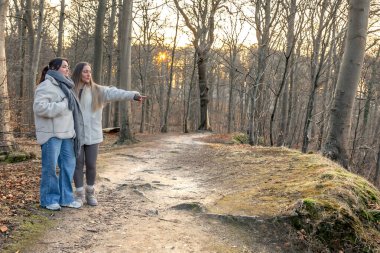 Ormanda iki kadın. Manzarayı gösteren bir kadın. Doğadaki insanlar. Yüksek kalite fotoğraf. Ormanda bir yürüyüş, doğada. İlkbahar, sonbahar mevsimi. Boşluğu kopyala.