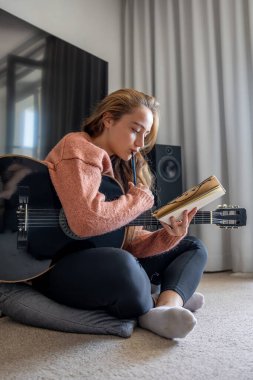 Genç kız evde gitar çalmayı öğreniyor. Müzik besteleyen kız. Gitar. Yüksek kalite fotoğraf. Kız evde gitar çalmayı öğreniyor. Gitar çalma alıştırması yapıyorum..