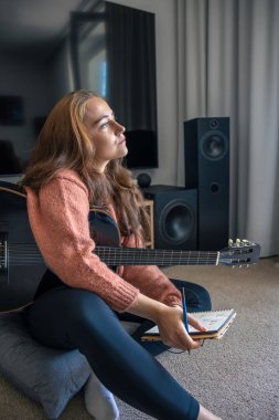 Genç kız evde gitar çalmayı öğreniyor. Müzik besteleyen kız. Gitar. Yüksek kalite fotoğraf. Kız evde gitar çalmayı öğreniyor. Gitar çalma alıştırması yapıyorum..