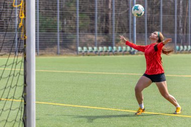 Futbol sahasındaki kız. Futbol antrenmanı. Aktif yaşam tarzı. Futbol konsepti. Yüksek kalite fotoğraf. Mesaj için yer var. Futbol formalı bir kız futbol topuyla oynuyor..
