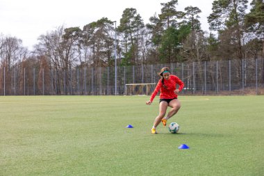 Futbol sahasındaki kız. Futbol antrenmanı. Aktif yaşam tarzı. Futbol konsepti. Yüksek kalite fotoğraf. Futbol formalı bir kız futbol topuyla oynuyor..