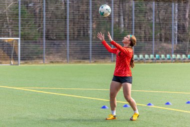 Futbol sahasındaki kız. Futbol antrenmanı. Aktif yaşam tarzı. Futbol konsepti. Yüksek kalite fotoğraf. Mesaj için yer var. Futbol formalı bir kız futbol topuyla oynuyor..