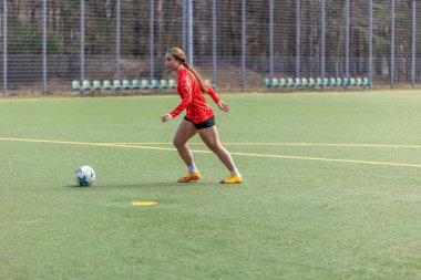 Futbol sahasındaki kız. Futbol antrenmanı. Aktif yaşam tarzı. Futbol konsepti. Yüksek kalite fotoğraf. Futbol formalı bir kız futbol topuyla oynuyor..