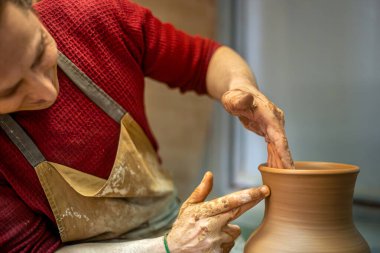 Usta erkek çömlekçi vazo yapıyor. Çömlek. Çamur modelliği. Seramik yapıyorum. Yüksek kalite fotoğraf. Vazo yapan bir erkek çömlekçinin ellerine yakın çekim.