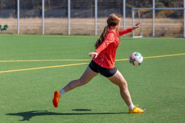 Futbol sahasındaki kız. Futbol antrenmanı. Aktif yaşam tarzı. Futbol konsepti. Yüksek kalite fotoğraf. Futbol formalı bir kız futbol topuyla oynuyor..
