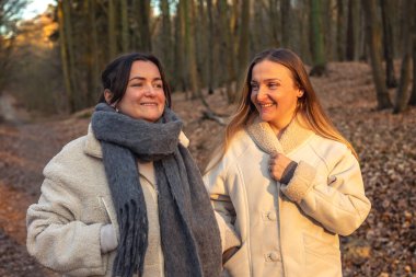 Ormanda yürüyüş yapan iki bayan arkadaş. Ormanda yürüyen arkadaşlar. Doğadaki insanlar. Yüksek kalite fotoğraf. Ormanda bir yürüyüş. Doğada rahatlama.